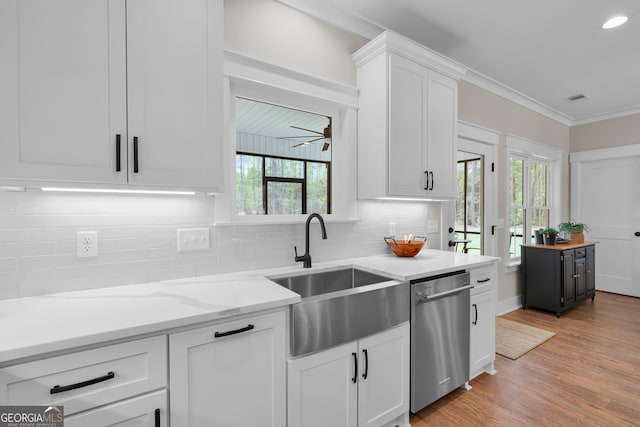 kitchen with dishwasher, a sink, white cabinets, backsplash, and light wood-style flooring