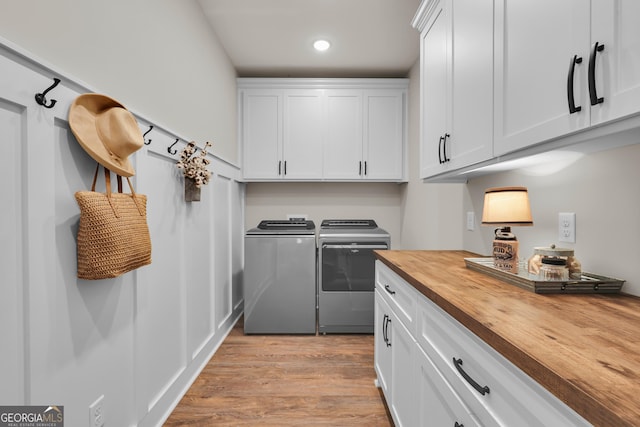 laundry room featuring cabinet space, washer and clothes dryer, light wood-style flooring, and recessed lighting