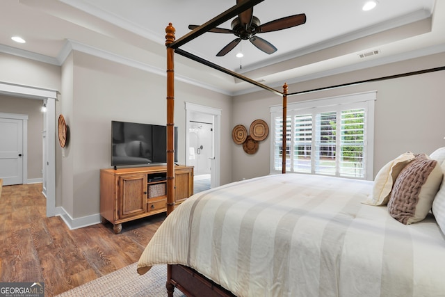 bedroom featuring ornamental molding, dark wood finished floors, a raised ceiling, recessed lighting, and baseboards