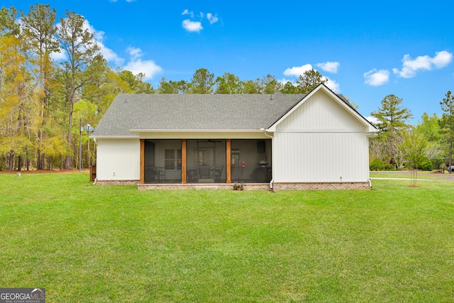 back of house with a sunroom, a lawn, roof with shingles, and a ceiling fan