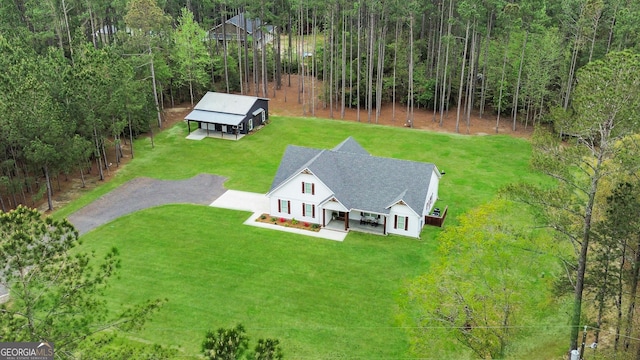 aerial view of property and surrounding area featuring a heavily wooded area