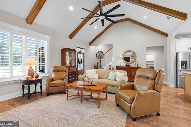 living area with ceiling fan, light wood-style floors, beamed ceiling, stairway, and high vaulted ceiling