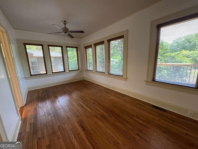 empty room featuring baseboards, a ceiling fan, and dark wood finished floors