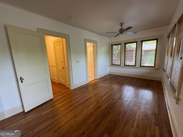 unfurnished room featuring dark wood-type flooring, a ceiling fan, and baseboards