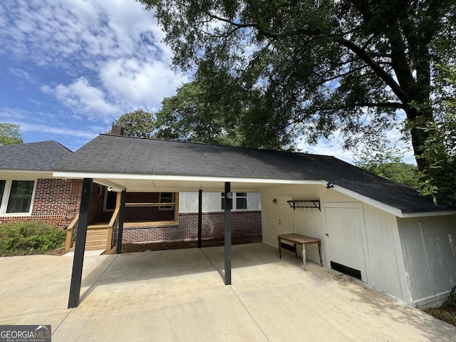 rear view of house with brick siding, concrete driveway, an attached carport, and a chimney