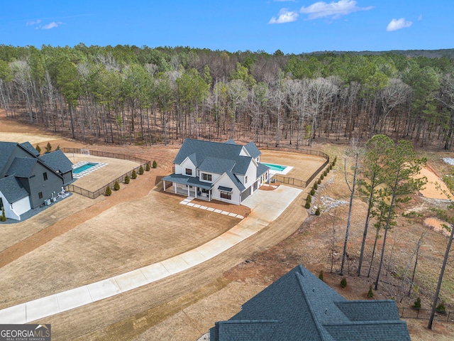 view of subject property featuring a heavily wooded area and a pool