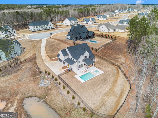 aerial perspective of suburban area featuring a pool and a heavily wooded area