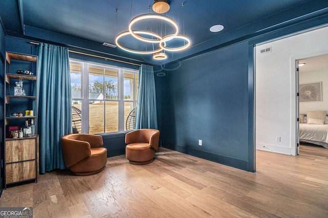 living area with wood finished floors, a chandelier, and baseboards