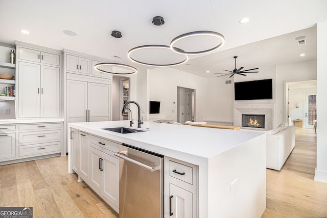 kitchen featuring a sink, ceiling fan, light wood-style flooring, a high end fireplace, and recessed lighting