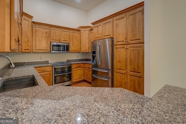 349 Bowen Hill Rd, Haddock, GA 31033 - kitchen with stainless steel appliances, a sink, brown cabinetry, and light stone counters