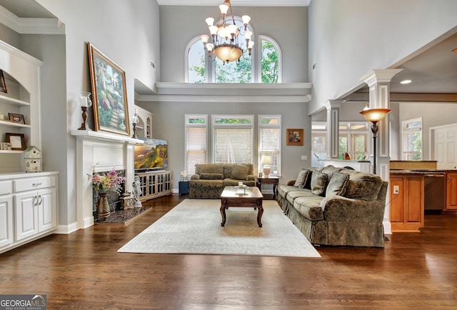 living room with a towering ceiling, dark wood-type flooring, a chandelier, and ornamental molding
