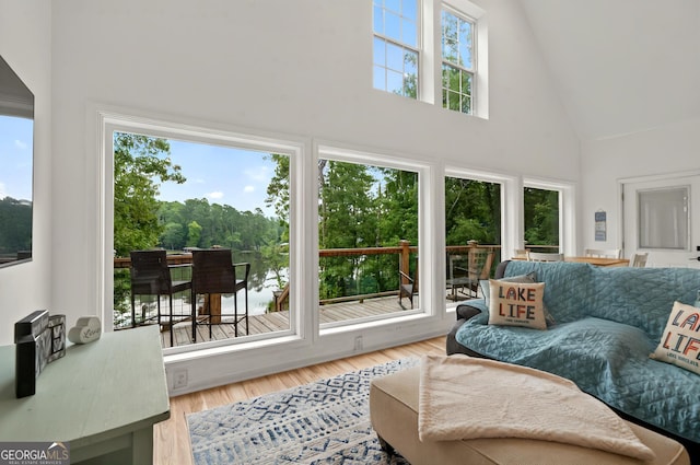 living room with high vaulted ceiling, healthy amount of natural light, and wood finished floors