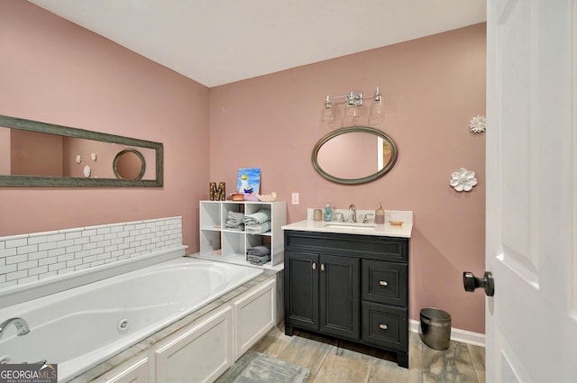 bathroom featuring a bath, vanity, baseboards, and wood finished floors