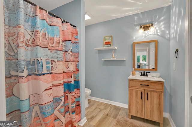 full bath featuring wood finished floors, vanity, toilet, baseboards, and curtained shower