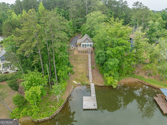 aerial view of property and surrounding area with a large body of water and a heavily wooded area