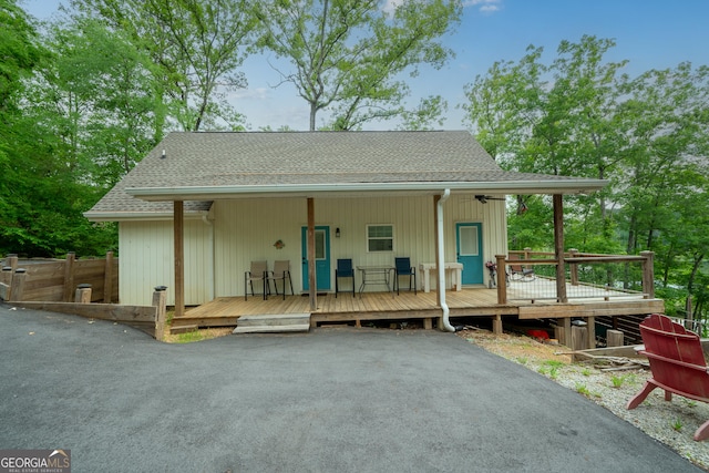 back of property featuring a shingled roof, a wooden deck, and fence