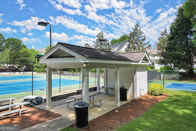 surrounding community with a tennis court and fence