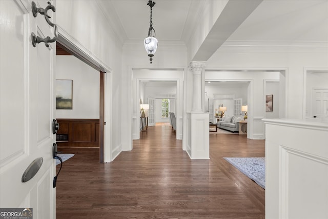entryway featuring decorative columns, ornamental molding, dark wood-style floors, a decorative wall, and wainscoting