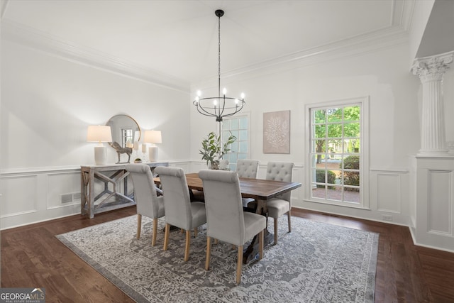 dining area with crown molding, ornate columns, a decorative wall, a chandelier, and dark wood-style floors