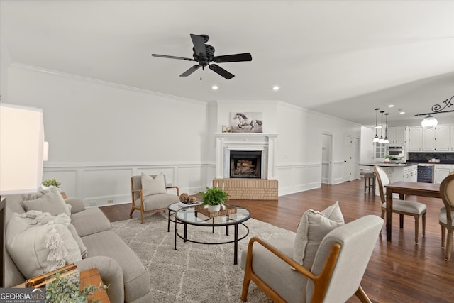 living area featuring crown molding, dark wood-style floors, ceiling fan, wainscoting, and recessed lighting