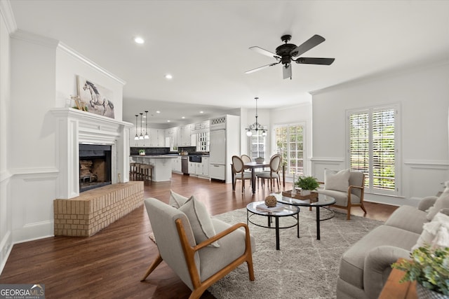 living area featuring a ceiling fan, crown molding, dark wood-style floors, recessed lighting, and a fireplace with raised hearth