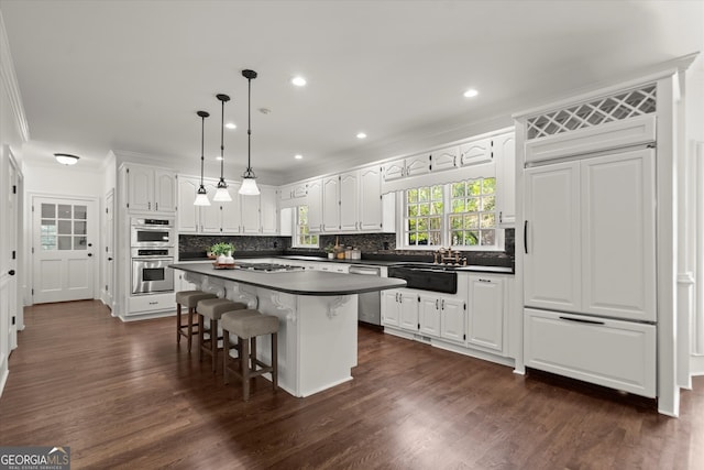 kitchen featuring dark countertops, appliances with stainless steel finishes, crown molding, white cabinets, and backsplash
