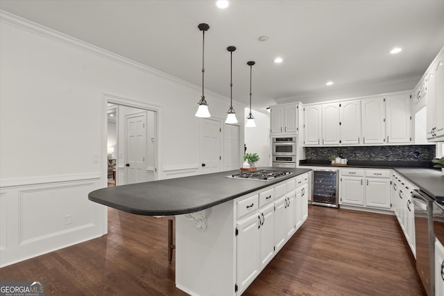kitchen featuring dark countertops, beverage cooler, crown molding, stainless steel appliances, and white cabinetry
