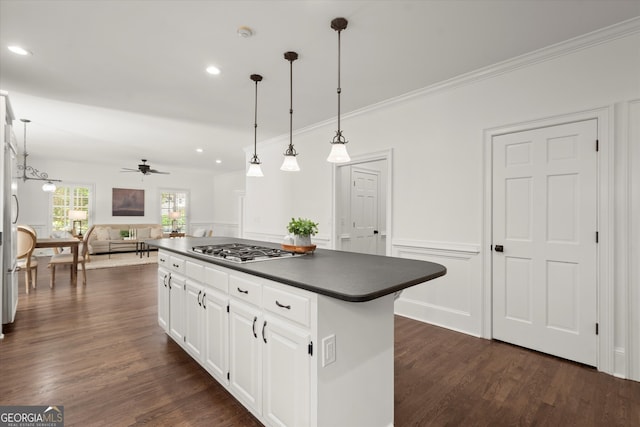 kitchen featuring dark countertops, stainless steel gas stovetop, open floor plan, a center island, and ceiling fan
