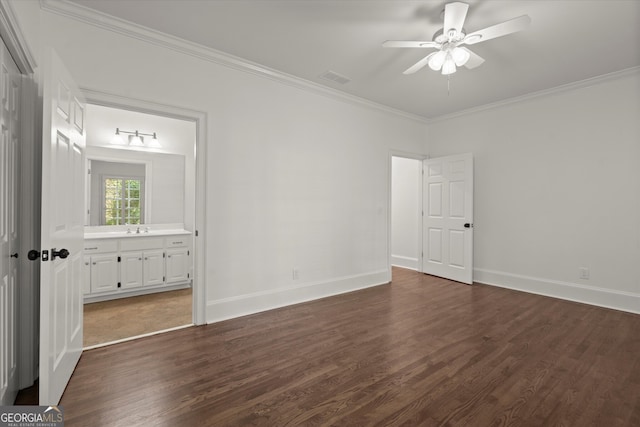 unfurnished bedroom featuring dark wood-style floors, ornamental molding, baseboards, a sink, and ensuite bathroom
