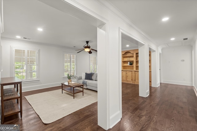 living room featuring attic access, crown molding, baseboards, ceiling fan, and dark wood-type flooring