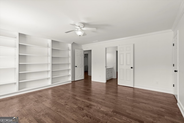 unfurnished bedroom with crown molding, dark wood finished floors, baseboards, ensuite bath, and ceiling fan