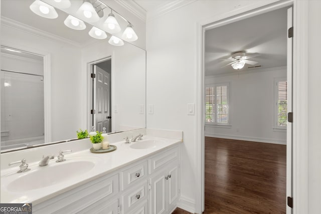 full bathroom featuring wood finished floors, a ceiling fan, crown molding, double vanity, and baseboards