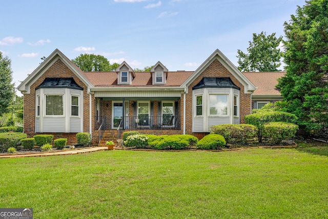 view of front of property featuring covered porch, brick siding, and a front yard
