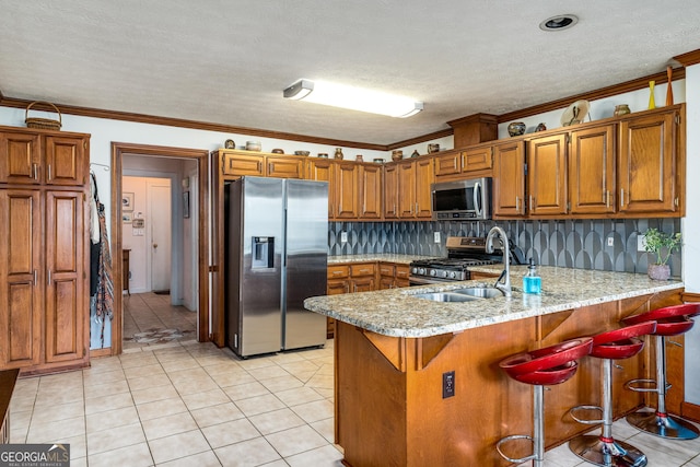 kitchen featuring stainless steel appliances, brown cabinetry, a peninsula, a sink, and ornamental molding