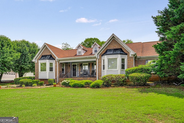 rear view of house with covered porch, brick siding, and a lawn