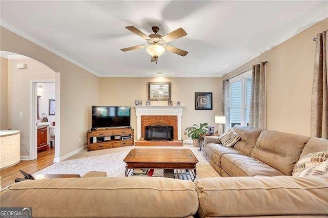 1105 Anemone Way NW, Acworth, GA 30102 - living room featuring arched walkways, ceiling fan, baseboards, a brick fireplace, and crown molding