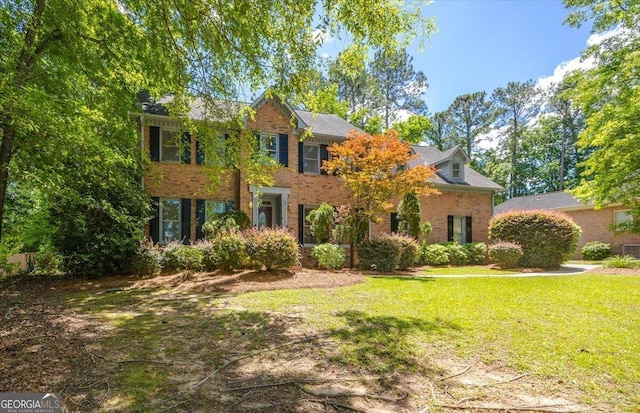colonial inspired home with brick siding and a front yard