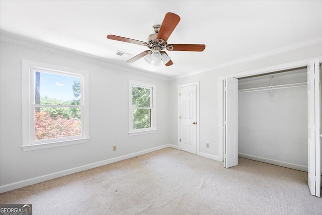 unfurnished bedroom featuring crown molding, baseboards, carpet, and a ceiling fan