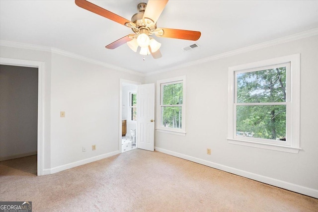 spare room with baseboards, healthy amount of natural light, ornamental molding, carpet, and a ceiling fan