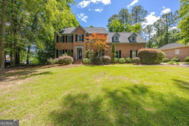 colonial inspired home with a front yard and brick siding