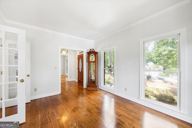 unfurnished room with ornamental molding, wood finished floors, and baseboards