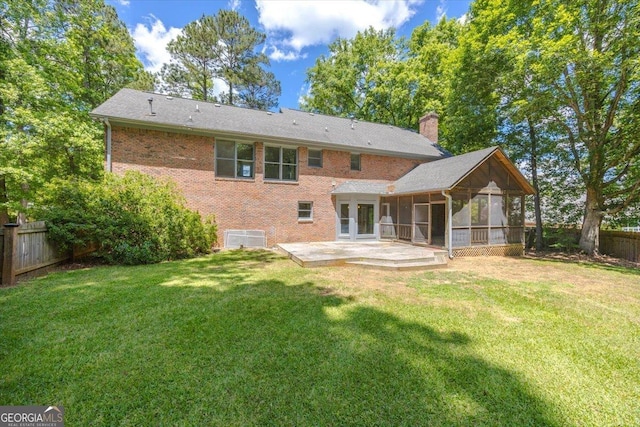 back of property featuring a sunroom, a patio, brick siding, and a chimney