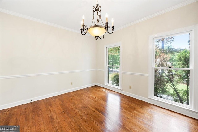 spare room with a chandelier, baseboards, wood finished floors, and crown molding