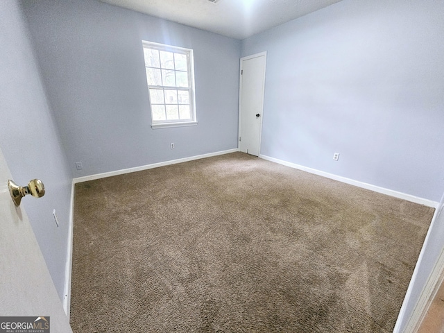 unfurnished room with carpet flooring and baseboards