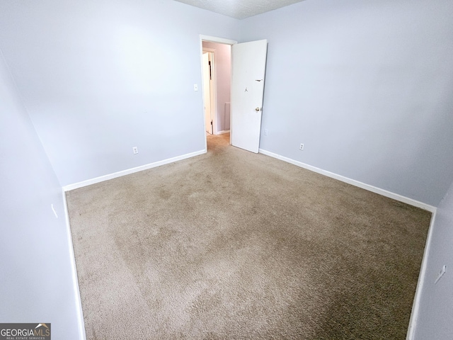 carpeted empty room featuring baseboards