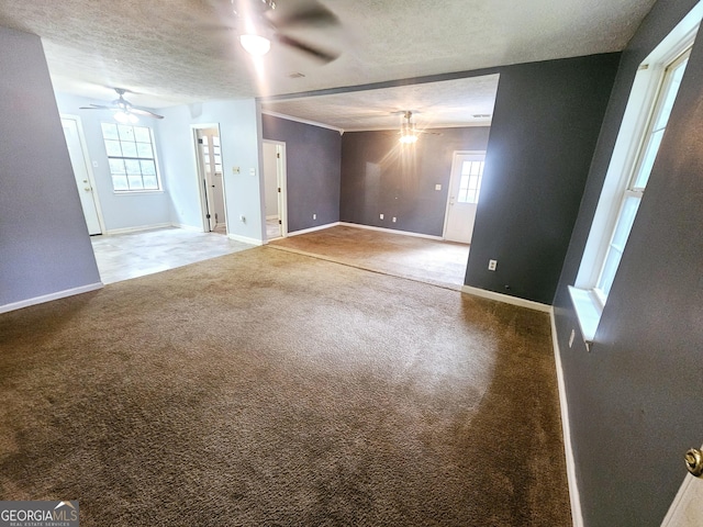 unfurnished room featuring ceiling fan, carpet, a textured ceiling, and healthy amount of natural light