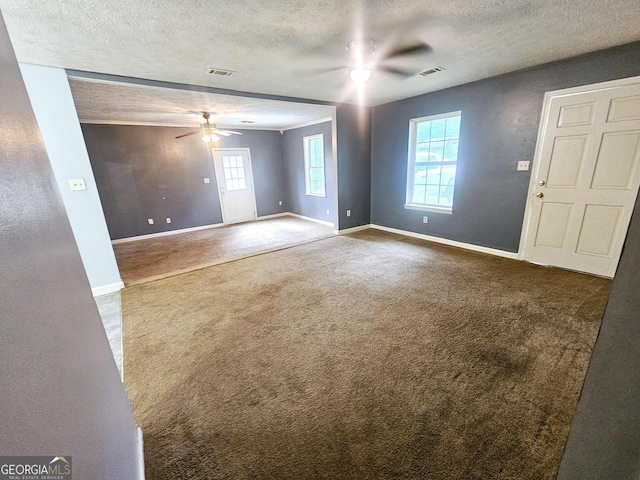 empty room featuring a ceiling fan, dark colored carpet, baseboards, and a textured ceiling