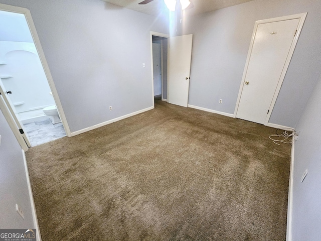 unfurnished bedroom featuring carpet floors, connected bathroom, baseboards, and a ceiling fan