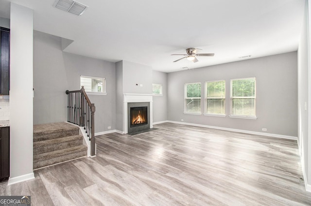 2769 Morgan Spring Trl, Buford, GA 30519 - unfurnished living room with a ceiling fan, plenty of natural light, light wood-style floors, and a fireplace with flush hearth