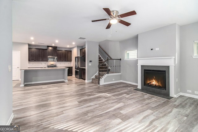 2769 Morgan Spring Trl, Buford, GA 30519 - unfurnished living room featuring light wood finished floors, a fireplace with flush hearth, a ceiling fan, stairway, and recessed lighting